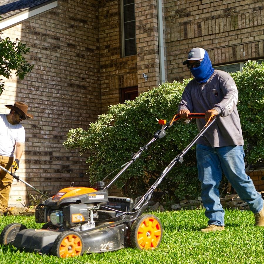 Two crew members mowing and trimming a residential lawn