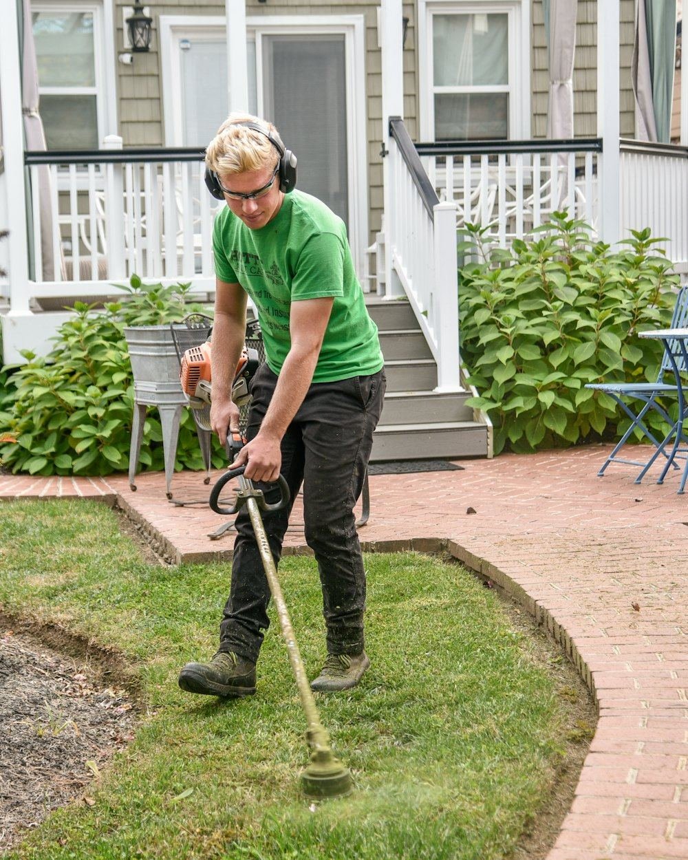 A landscaper in a work shirt holding a shovel