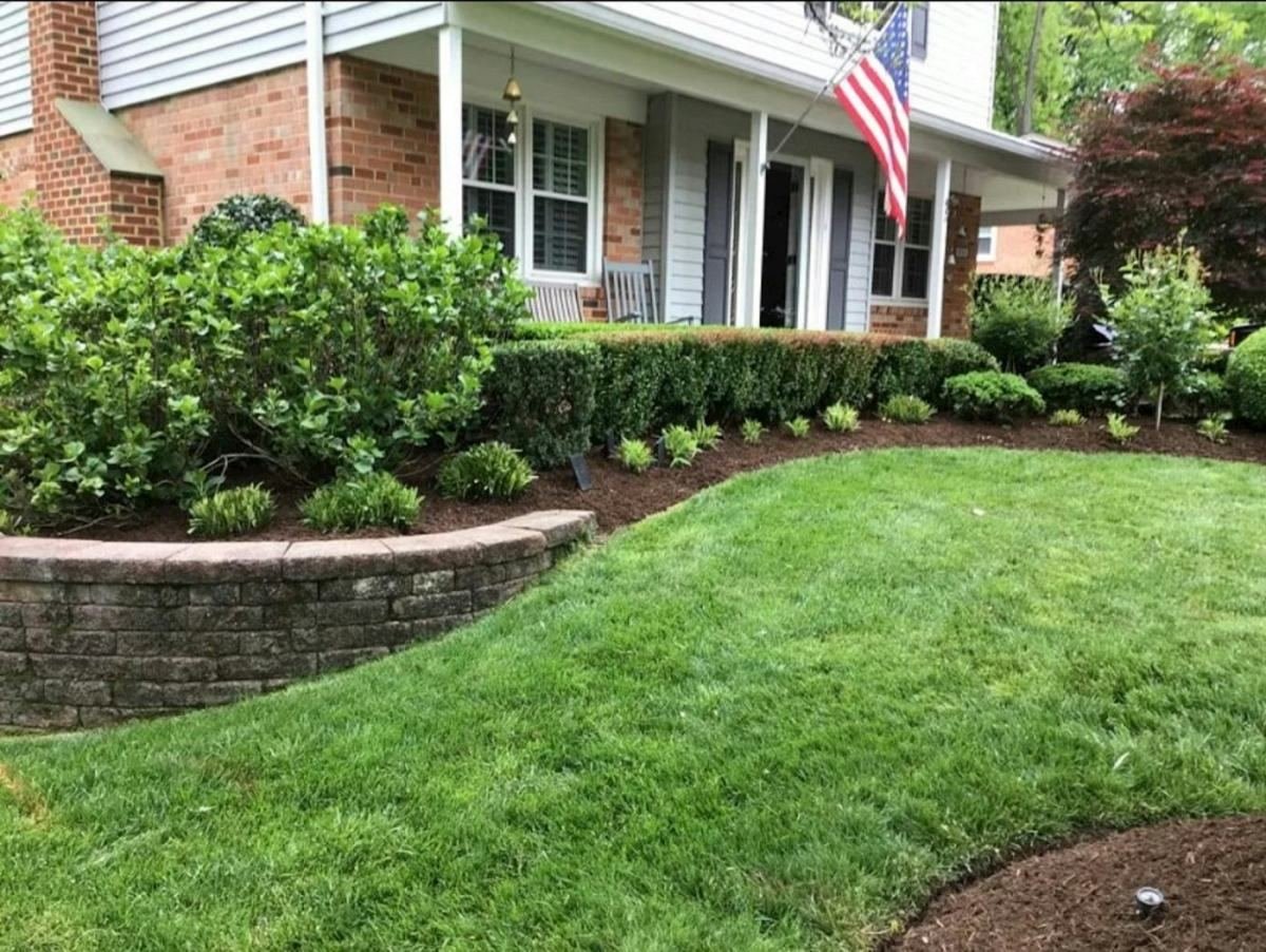 A brick home with a trimmed lawn, low retaining wall and foundation planting