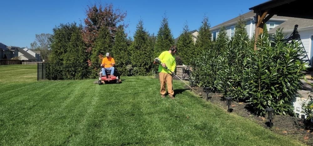 Two groundskeepers mowing and trimming a large striped lawn in Norwalk, CT